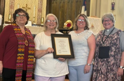 Church leaders standing together holding a framed 285th anniversary certificate.